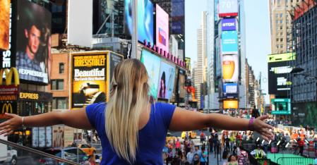 AuPairCare Connect au pair med utsträckta armar på Times Square