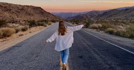 Au pair springer med utsträckta armar längs motorvägen i öknen