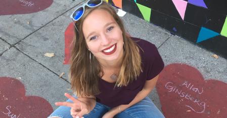 Au pair sitter i skräddarsydd position på golvet och ler mot kameran